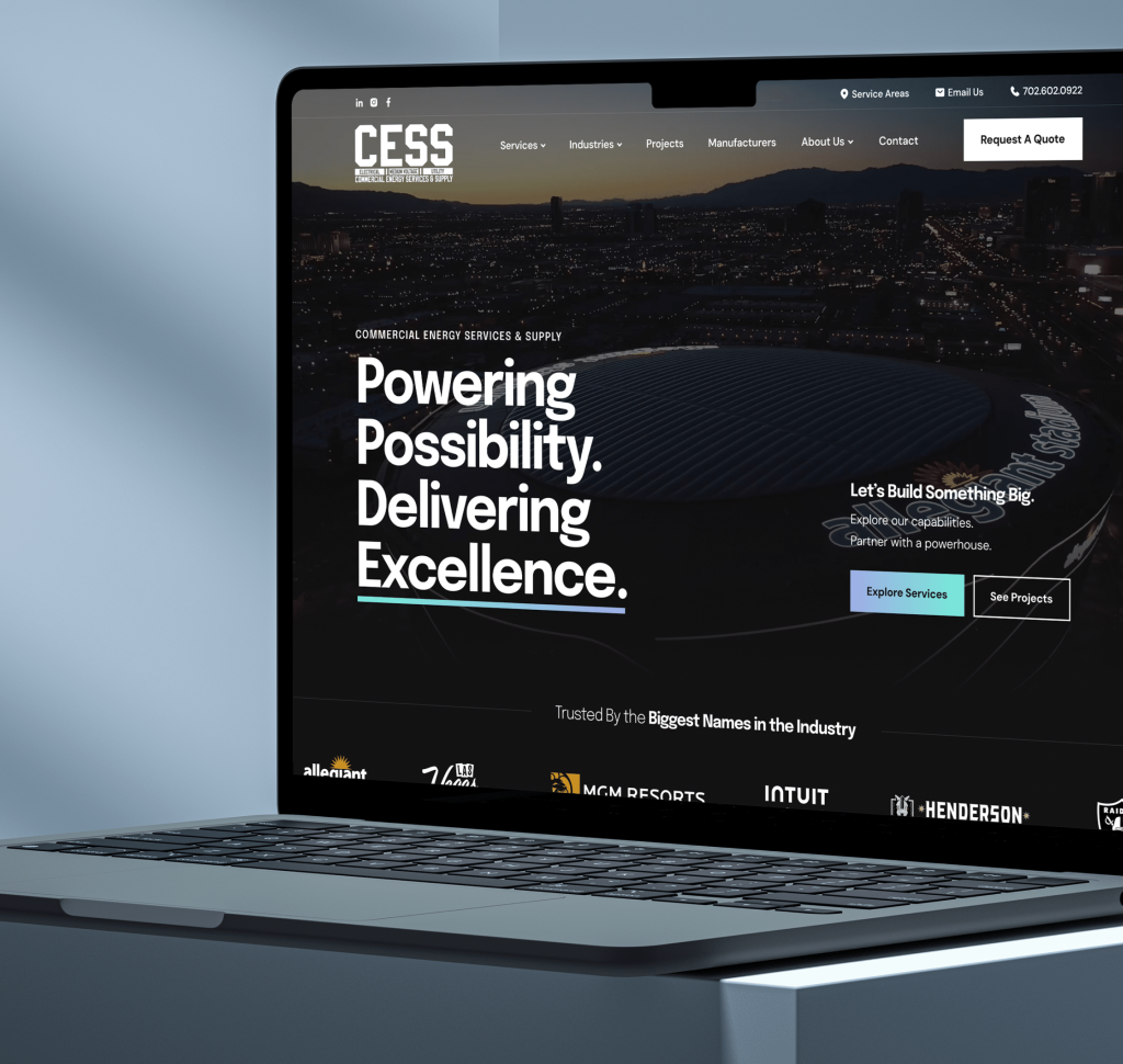 A laptop displaying a website with "Powering Possibility. Delivering Excellence." over a night city skyline.