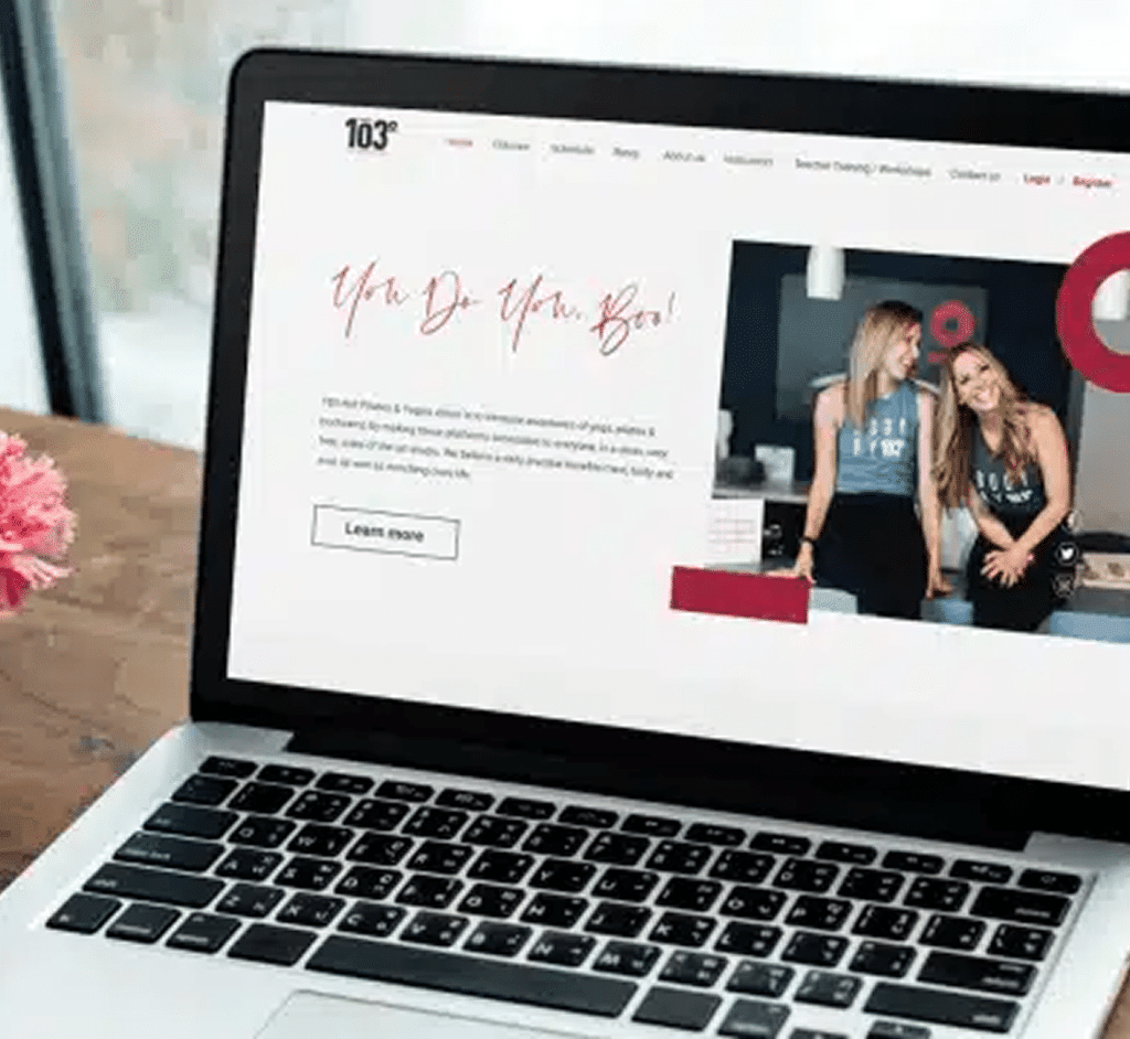 A laptop displays a website with the text "You Do You, Boo!" and two smiling women.