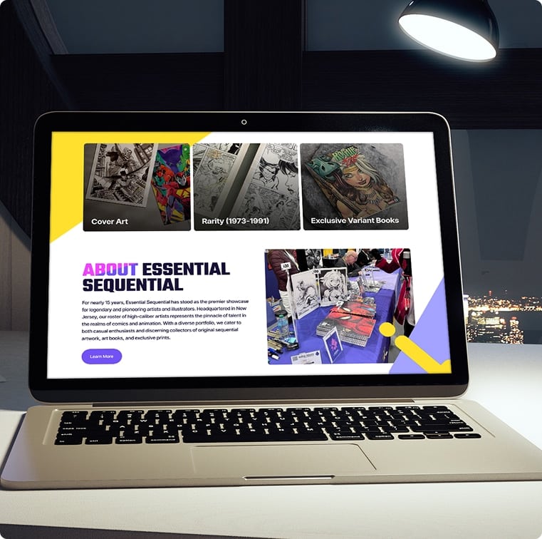 A laptop displays a website with "ABOUT ESSENTIAL SEQUENTIAL" and comic art categories, under a desk lamp.