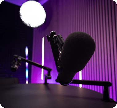 Two black microphones on a dark table in a room with purple lighting and a bright white orb light.