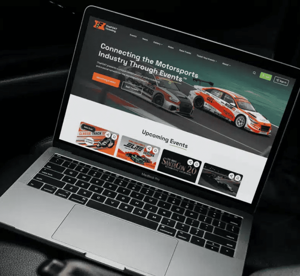 A MacBook Pro displays "TheFOAT Ticketing" website with two race cars and "Connecting the Motorsports Industry Through Events."