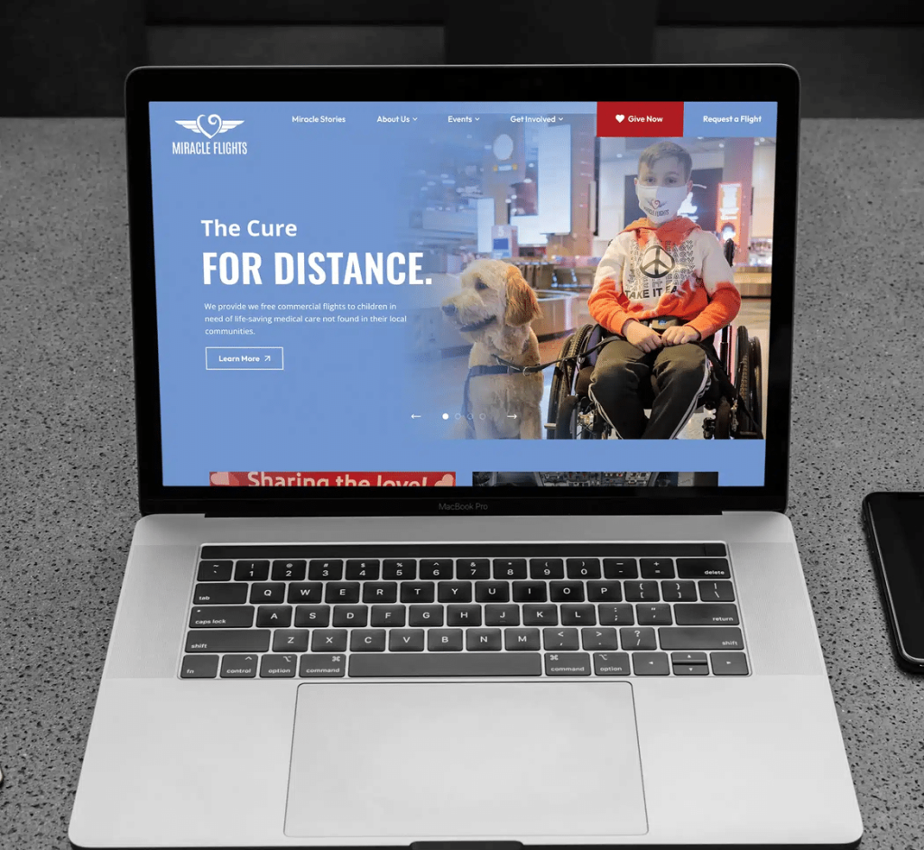 A MacBook Pro displays the "Miracle Flights" website with a child in a wheelchair and a service dog.
