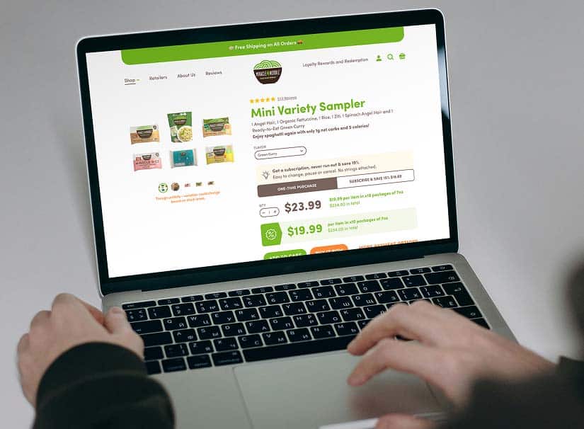 Hands type on a laptop displaying a website for "Mini Variety Sampler" with prices "$23.99" and "$19.99."